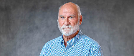 A man with a beard and mustache wearing a blue striped shirt. Description generated by AI