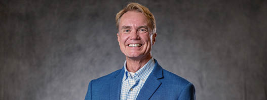 A man wearing a blue jacket and a white shirt is smiling for the camera. AI generated content
