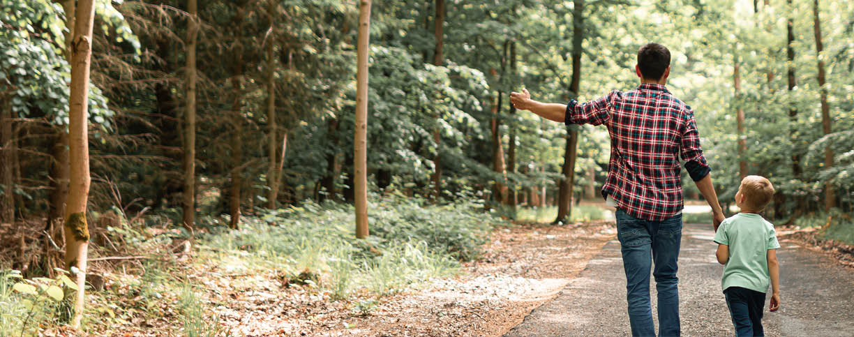 A man and a child are walking down a road in the woods. AI generated content